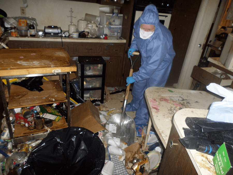 a hoarder cleaning specialist in protective gear tackles gross filth in a kitchen.png